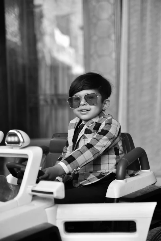 a child with 3d glasses sitting on a toy car