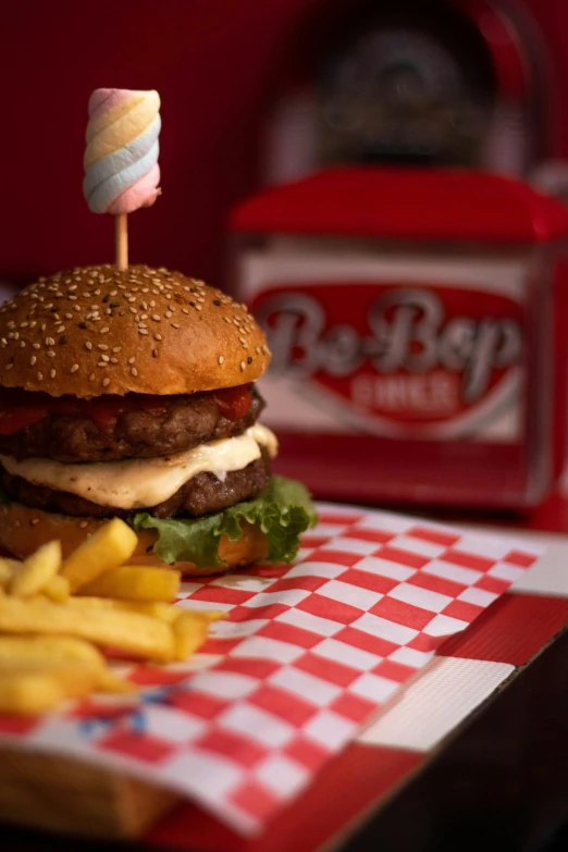 hamburger with a marshmallow on the top sitting next to fries