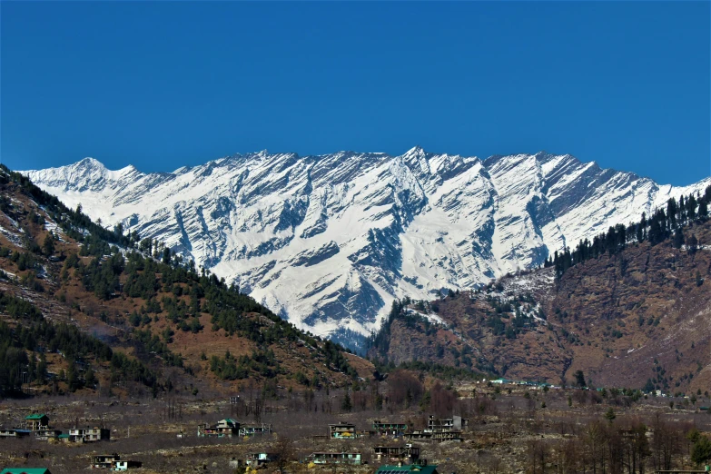 a snow - covered mountain is shown with houses and green homes