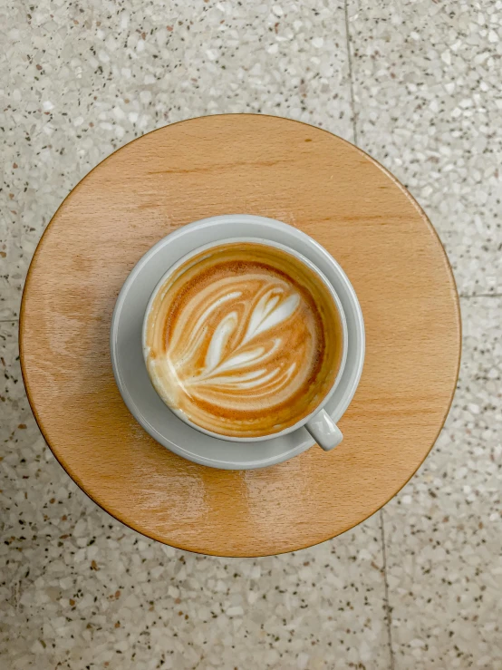 a cappuccino on a saucer is sitting in the center of a table