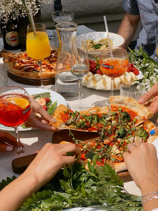 people are sitting around a dinner table with different foods and drinks