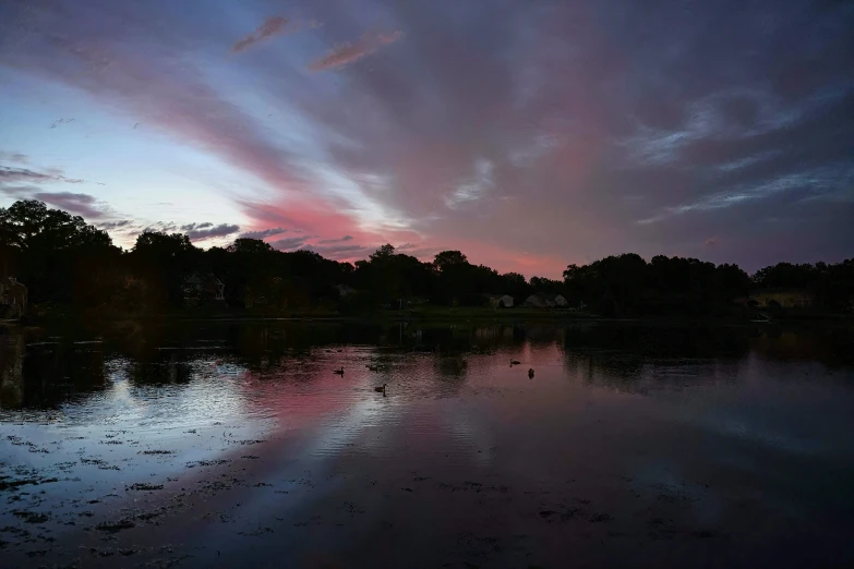 a lake with trees and blue sky at dusk