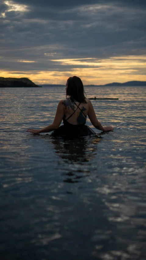 a woman riding a paddle board in the ocean at sunset