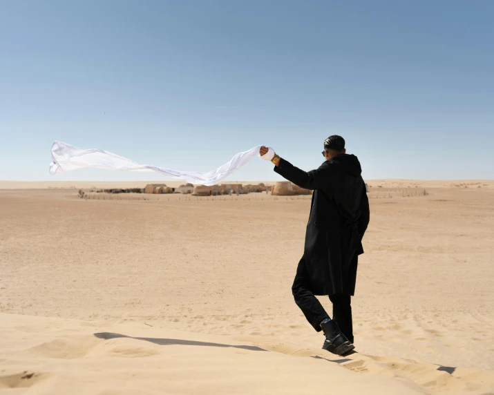 a man stands on the sand and is holding soing in his hand