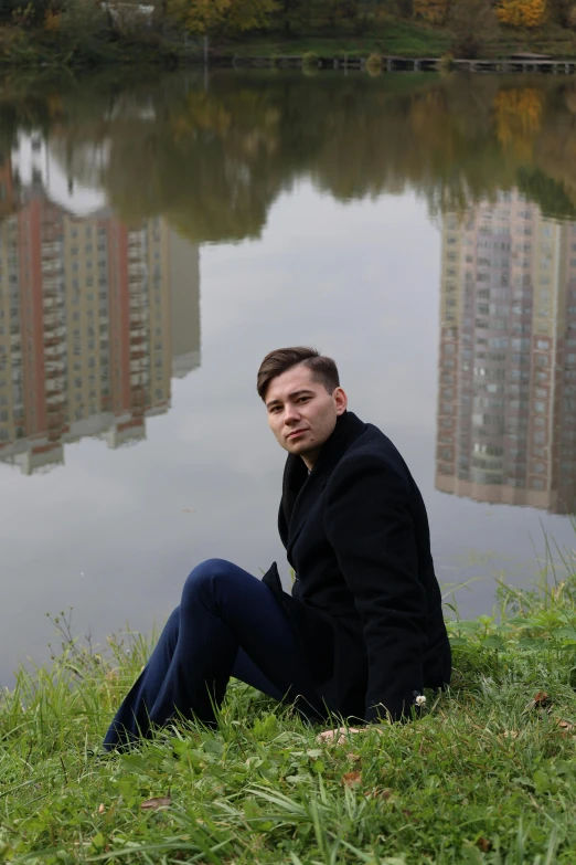 a man sitting by a river near a body of water