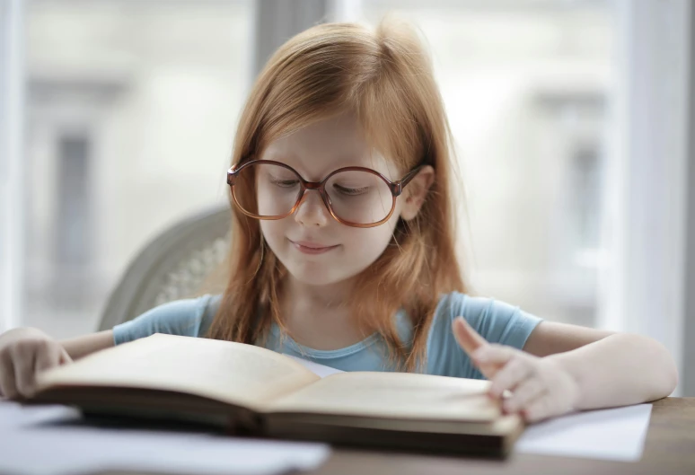 a girl is reading a book with glasses