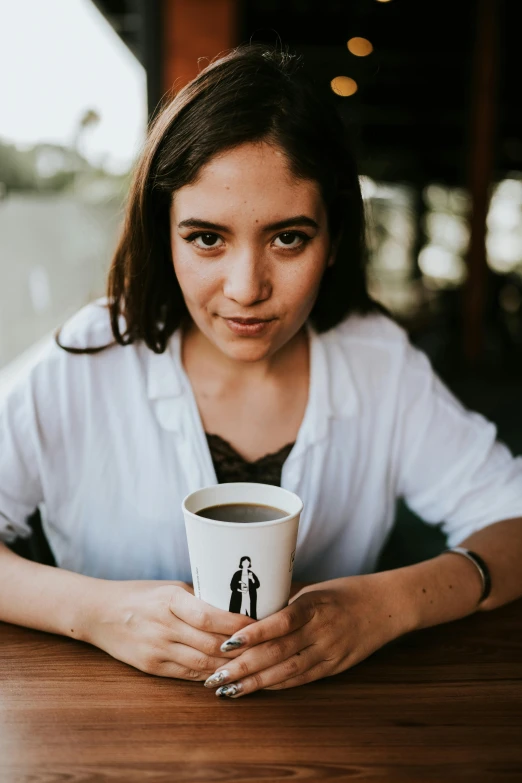 the lady is holding a cup on a table