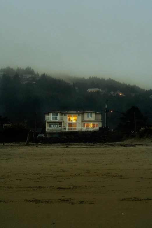 a large house lit up with yellow lights by a body of water