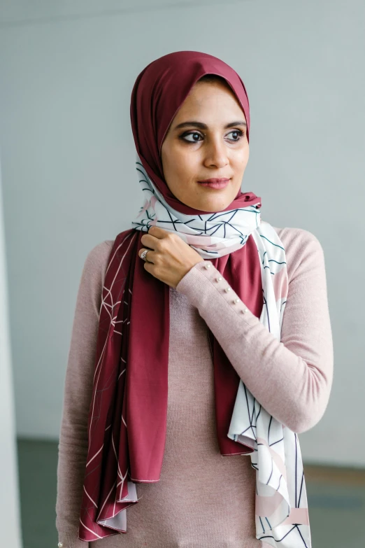 a woman in a pink sweater stands by a window