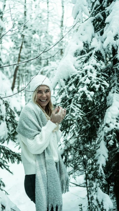 a smiling woman standing in a snowy wooded area