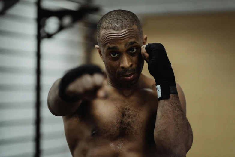 shirtless male boxer using an exercise ball in a gym