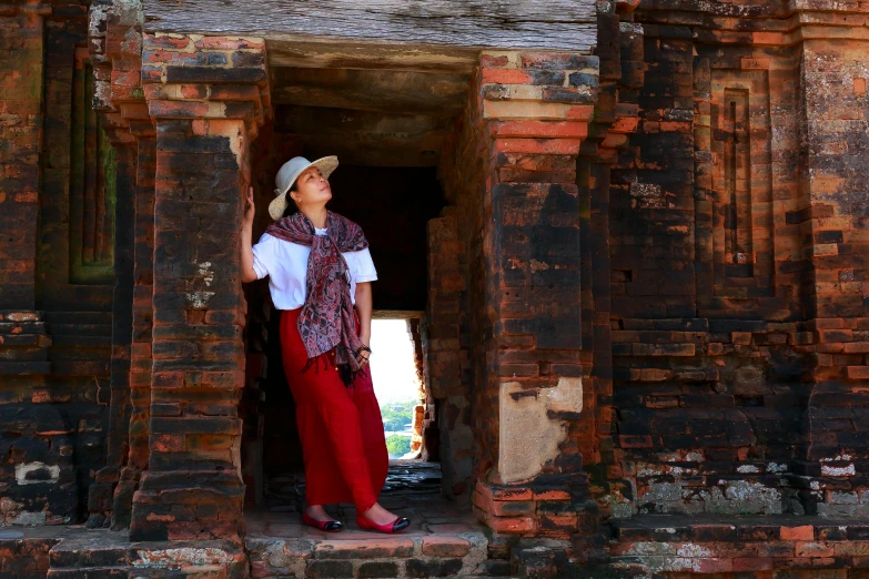 woman in red pants and white top standing near brick doorway