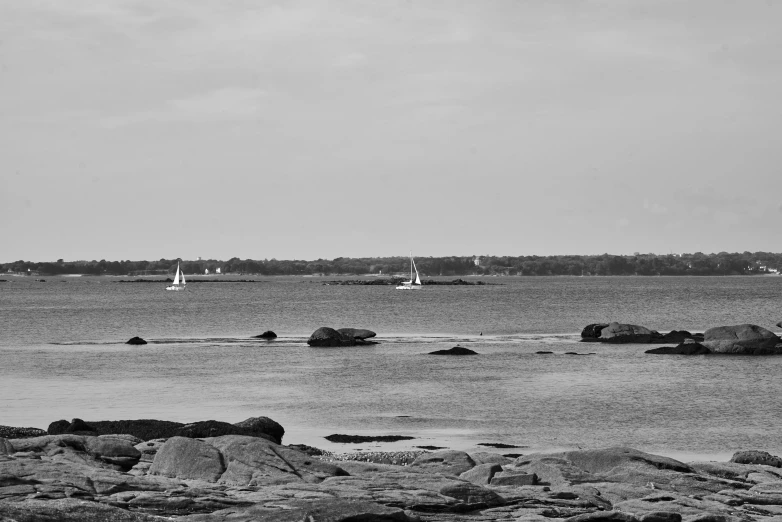 three sailboats in the water at a beach