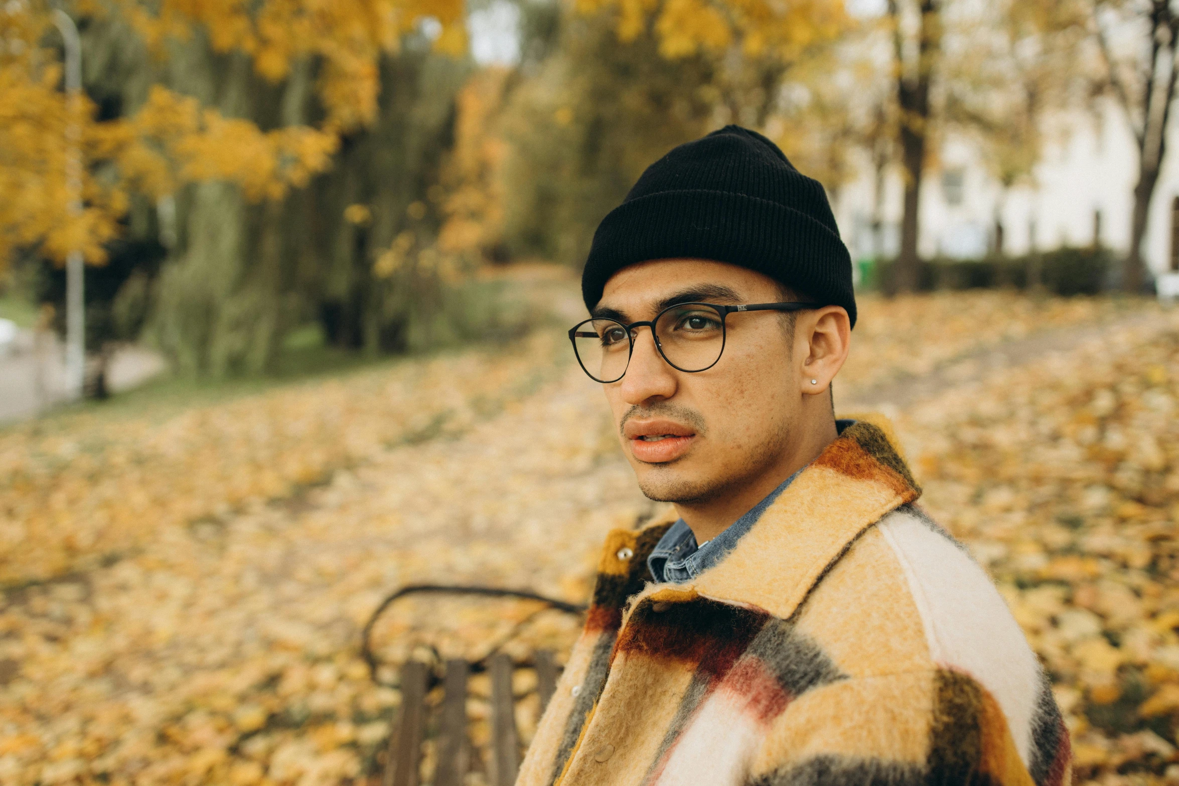 the man is wearing glasses and standing by leaves