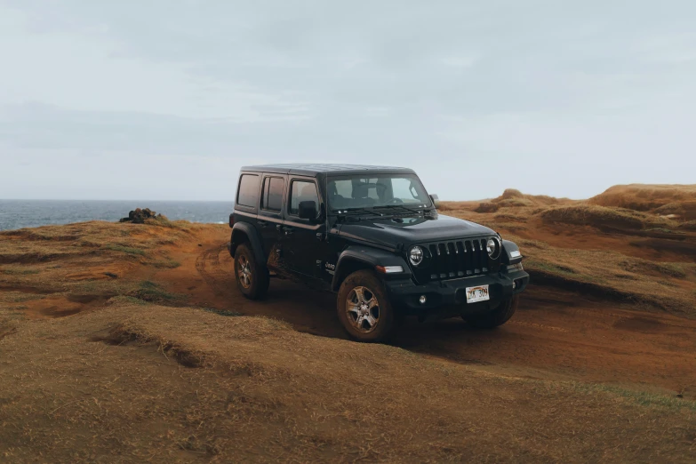 jeep sitting on the edge of hill overlooking sea