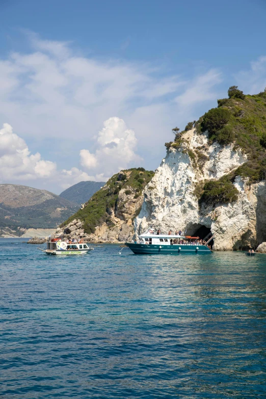 some boats on the water in front of some cliffs