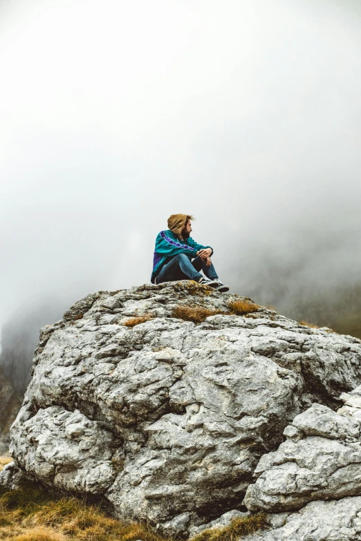 the man is sitting on top of the rocky hill