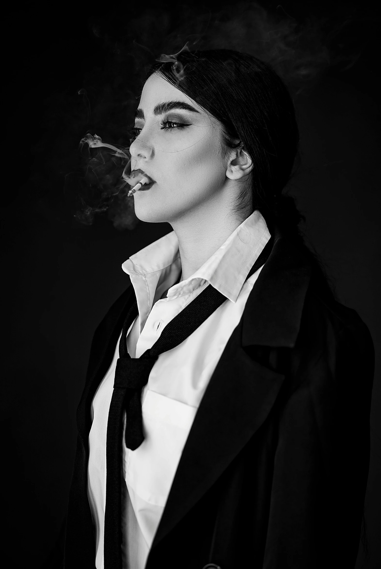 a woman wearing a tie and smoking a cigarette