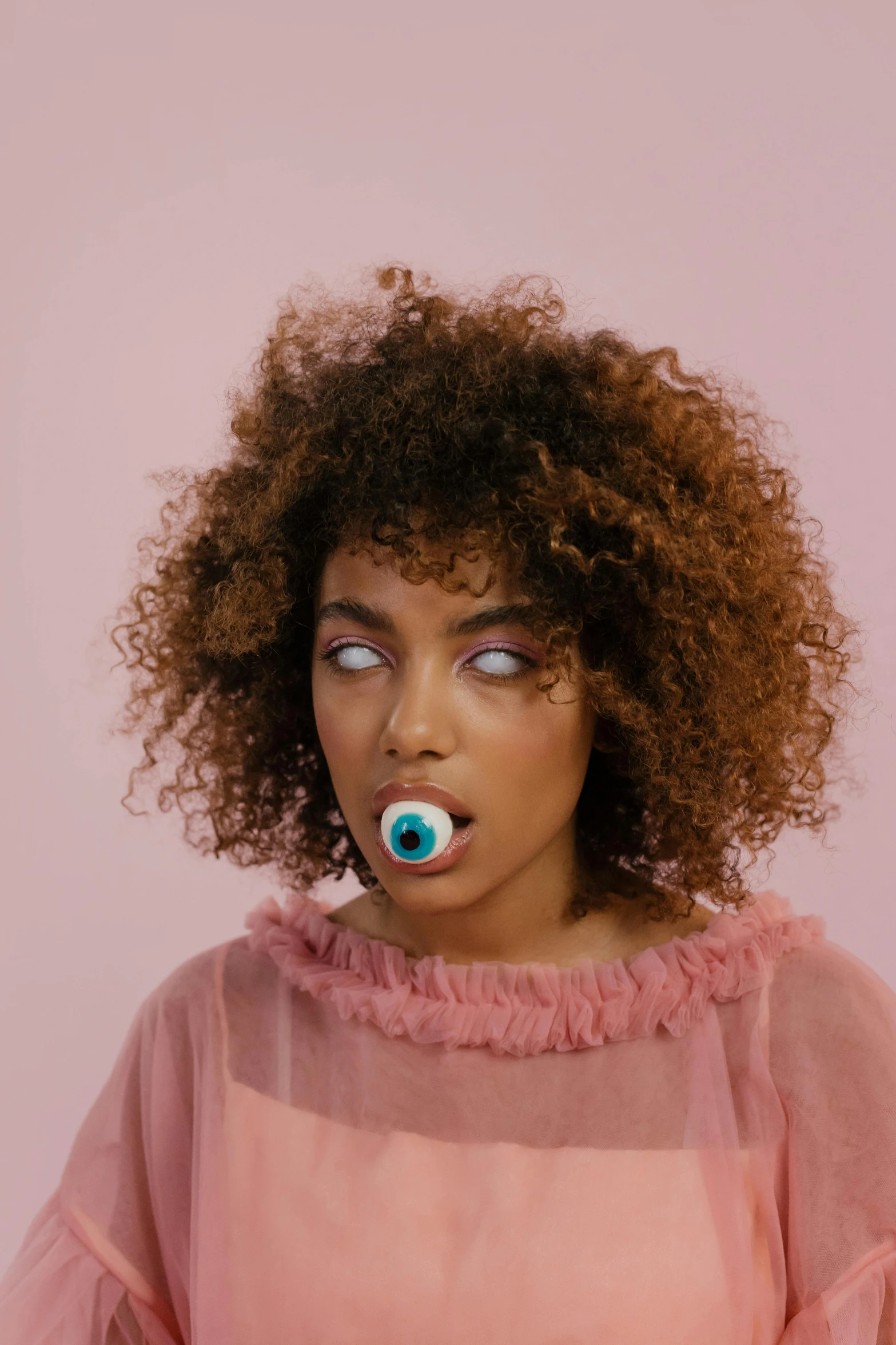 an african american woman with afro hair and blue blue eyeliners looks into the camera