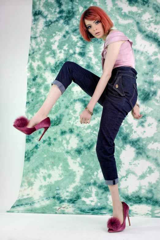 a girl in black tight pants and high heel shoes posing in front of a green and white backdrop