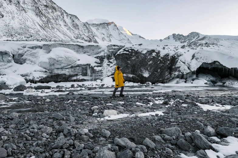 a person in yellow standing on rocks and rocks