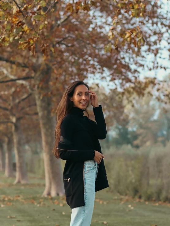 a woman stands in a park holding her phone