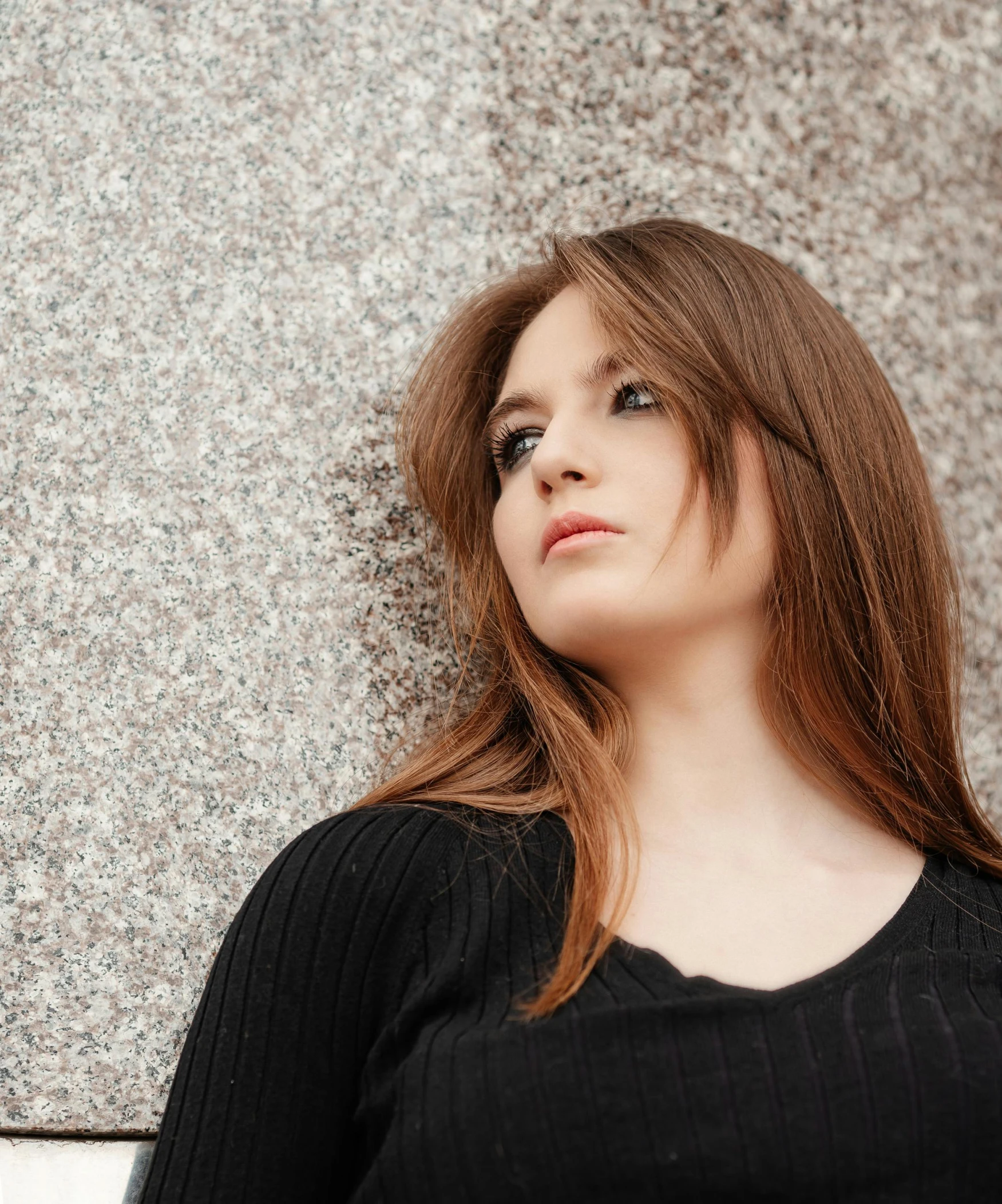 a woman with long red hair leaning against the wall