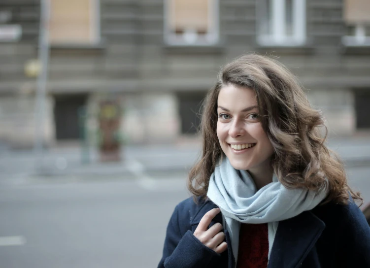 a woman with long hair wearing a coat and scarf smiles