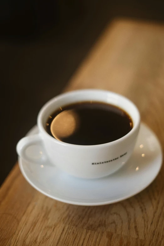 a cup of coffee sits on a saucer on a wooden table