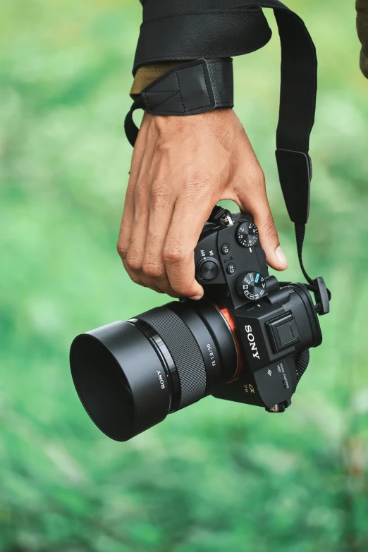 a hand holding a camera, showing the lens