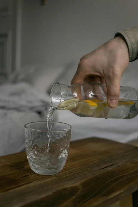 someone pouring water into a glass on top of a table