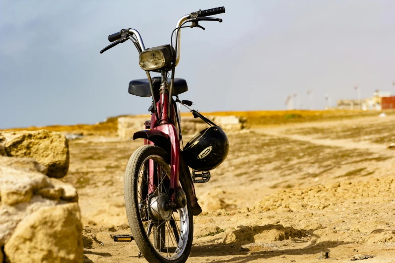 a red bike is parked on the dirt and some rocks