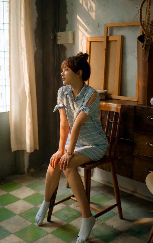 woman in dress sitting on a chair with green checkerboard flooring