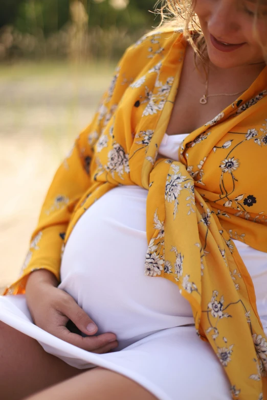 a pregnant woman sits and looks down at her stomach