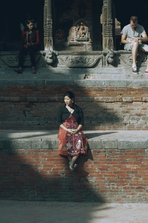 people sit on steps near a fountain with buddha statues