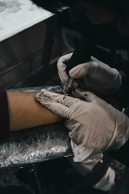 a person with glove on getting their tattoo done