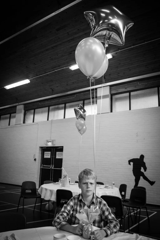 man sitting at table in indoor banquet hall with balloons