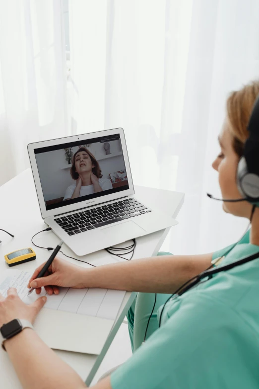 a person is sitting at a desk with a laptop and headphones