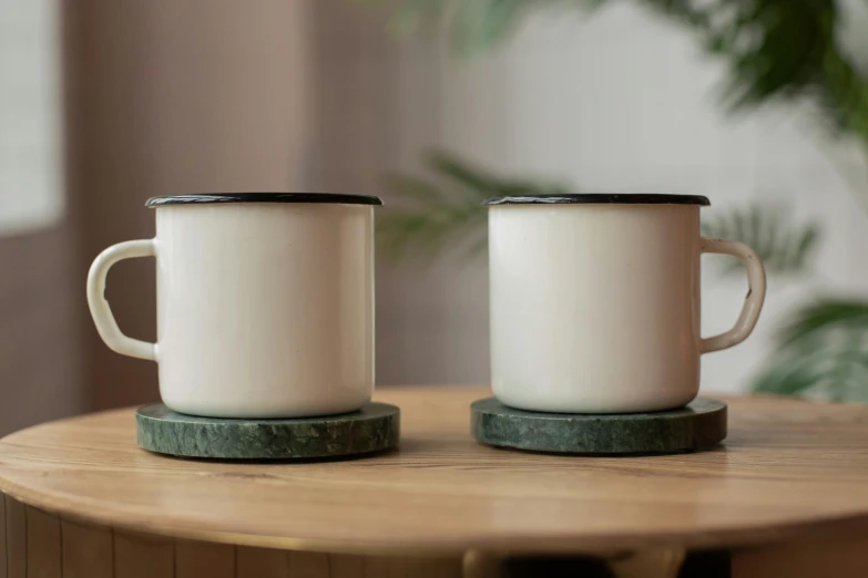 two white coffee mugs sit on a wooden table