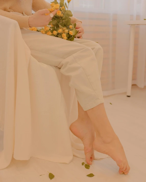 a person sitting on top of a bed with flowers in their feet