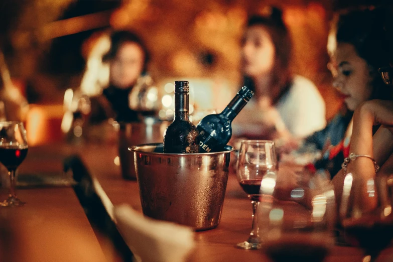 people are gathered around the bar with wine bottles and glasses