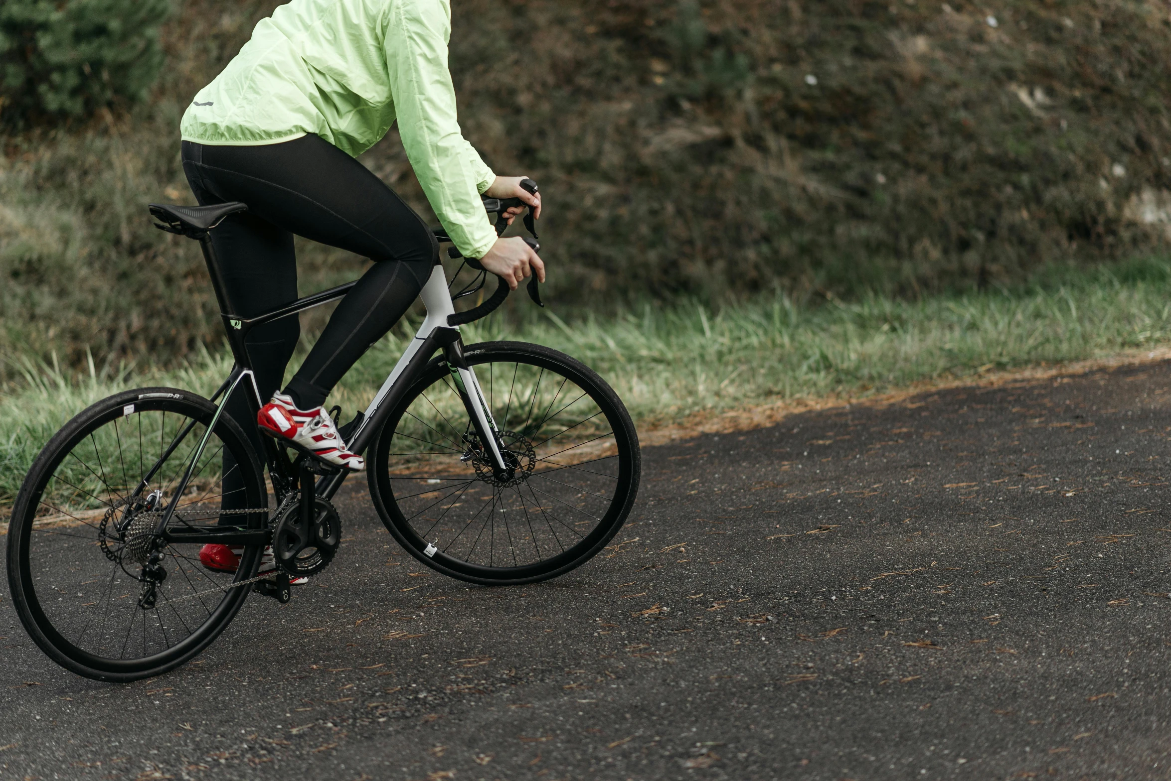 woman in yellow jacket and black pants riding bicycle down road