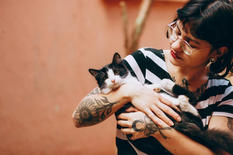 a young woman is holding a cat on her lap