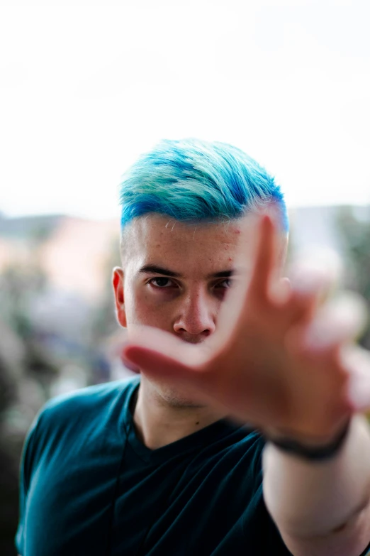 a boy with bright blue hair is gesturing