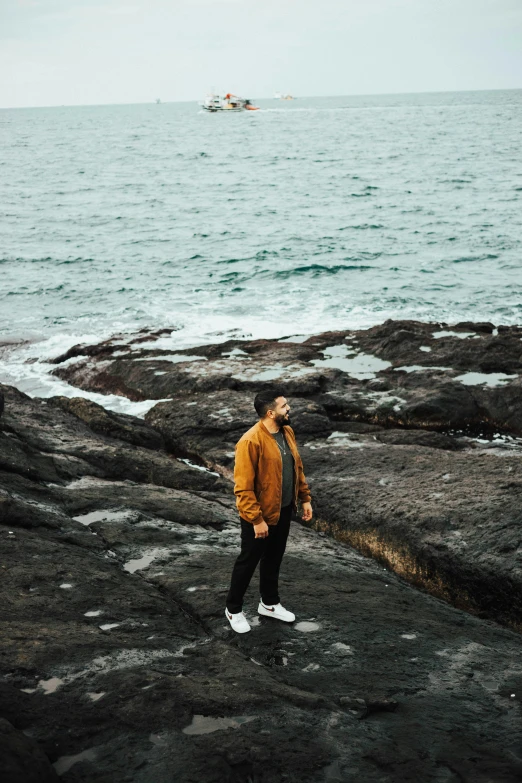 a man standing on rocks looking out at the water