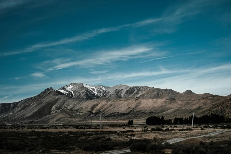 snow covered mountains rise above a dirt road