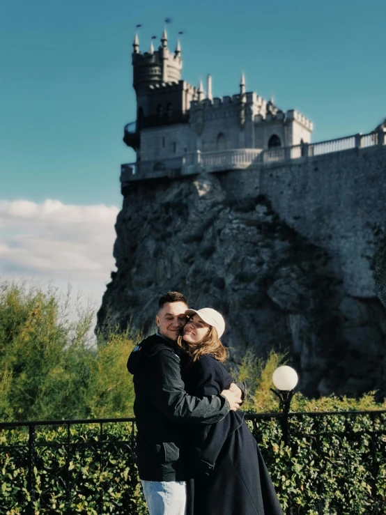 a woman and man posing in front of a castle