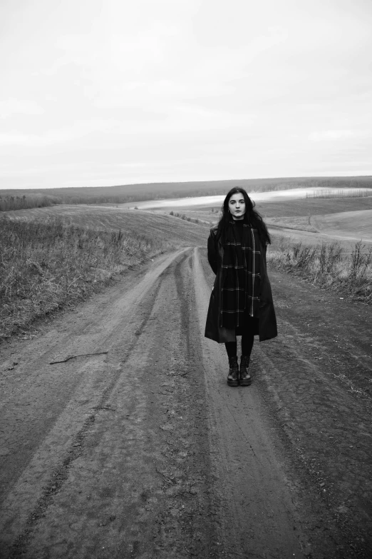 a woman in a coat on a dirt road