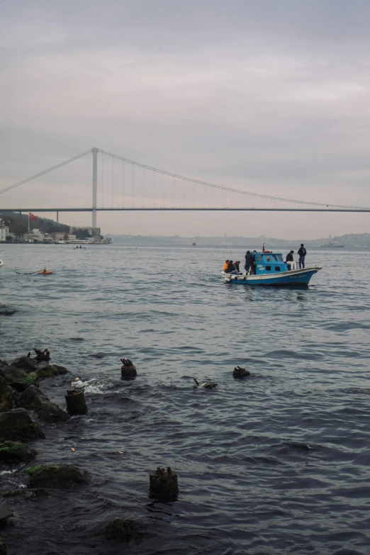 several people standing on a blue boat near water