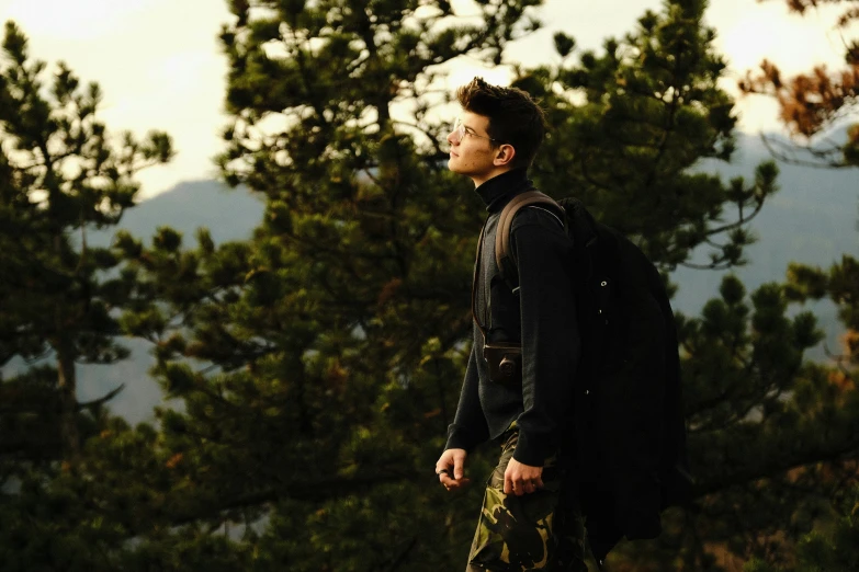 a man with a backpack standing near some trees